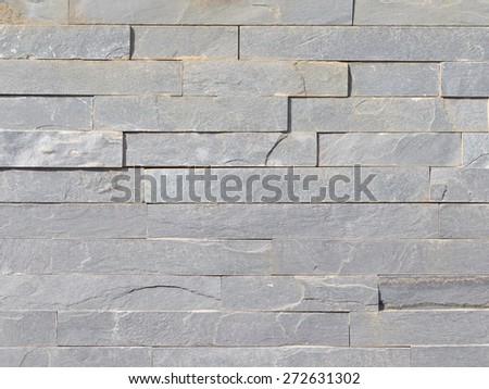 Wall of natural light shining gray stone laid as a brick