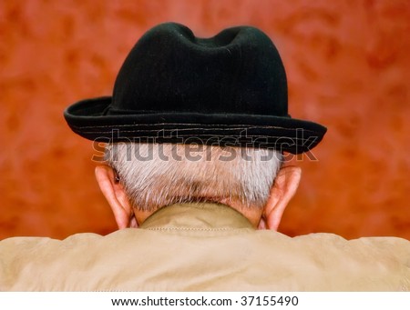 old man behind the counter in the rear view of black hat and cloak