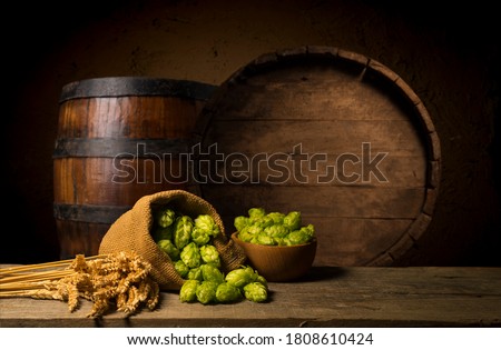 Beer. Still life with Vintage beer barrel and glass light beer. Fresh amber beer concept. Green hop and gold barley on wooden table. Ingredients for brewery. Brewing traditions ストックフォト © 
