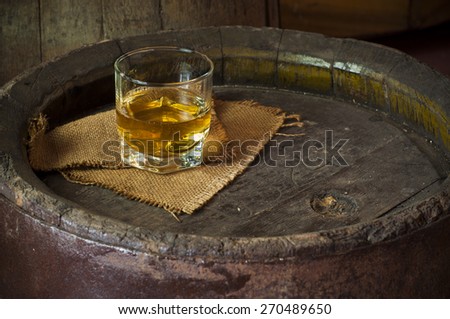 A glass of whiskey  on an old oak barrel