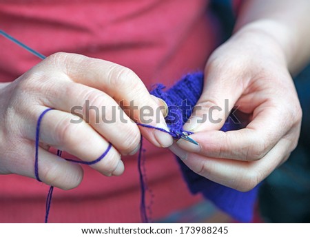 Woman knitting with blue wool.