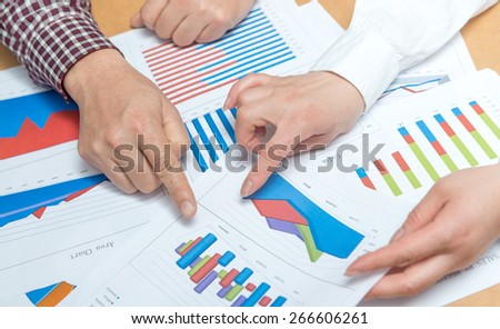 Business people discussing the charts and graphs showing the results of their successful teamwork