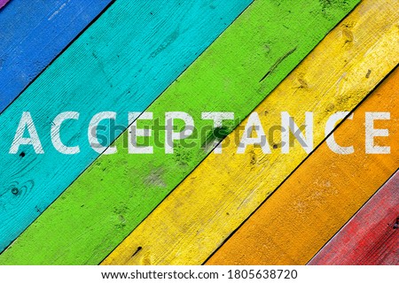 Background with a rainbow-colored LGBT community wooden surface with the words ACCEPTANCE. Concept - acceptance and agreement with LGBT people