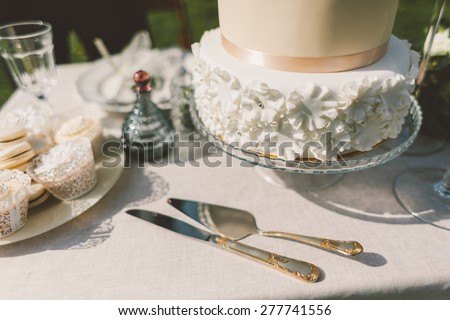 wedding cake with fondant cakes and macaroons on the table knife fork spatula and decor