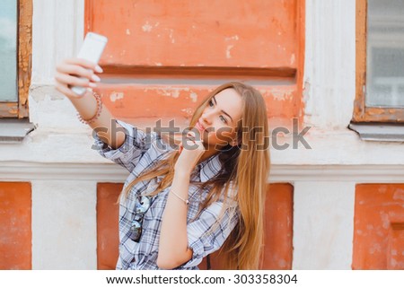 pretty girl make a duck face, and take a self portrait with her smart phone,smiling and having fun,waiting for friends,close-up cute smiling woman outdoor.