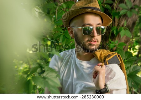bearded man in sunglasses and a hat, posing in nature