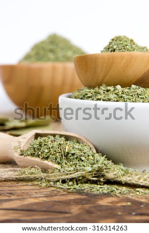 Photo of bowls and wooden spoon full of marjoram with white space