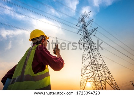 Picture of an electrical engineer standing and watching at the electric power station to view the planning work by producing electricity at high voltage electricity poles.