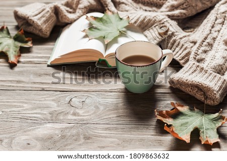 Autumn morning coffee. A cup of coffee on a wooden table and a warm sweater on a background of autumn leaves. Still life concept. Copy space. Stockfoto © 
