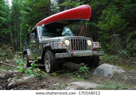 LISCOMB, NOVA SCOTIA - JUNE 15, 2005:  A Jeep Wrangler 4x4 travels through a rough trail in the woods to reach a remote lake for a canoe trip.