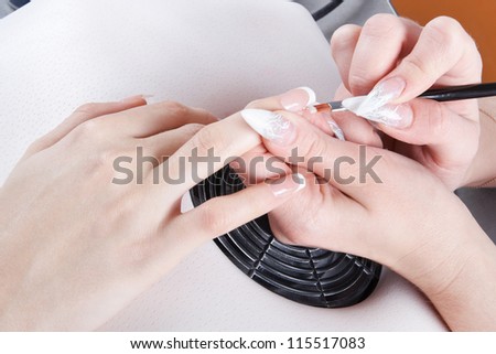 Manicure. Master make nail extension: drawing of white gel on free edge of a nail