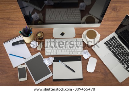 Laptop, smartphone, tablet, pen tablet and coffee cup with financial documents on wooden table