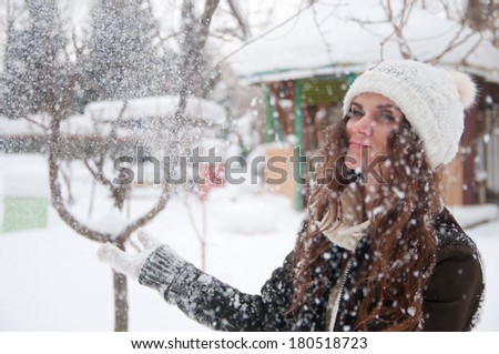 Beautiful girl throws snow in winter park