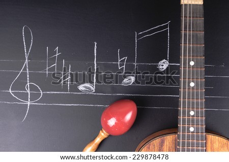 Vintage guitar and maracas on a chalkboard with music notes