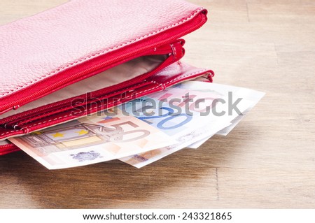 Open red wallet with euro banknotes on wooden background