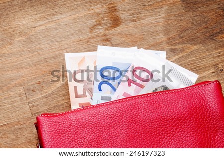 Open red wallet with euro banknotes on wooden background