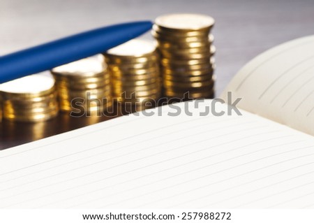 rows of gold stack coins, pen and note