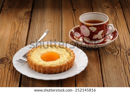 Peach tart and cup of black tea on wooden background