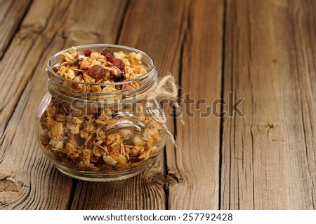 Granola in jar with packing-twine on wooden background with space