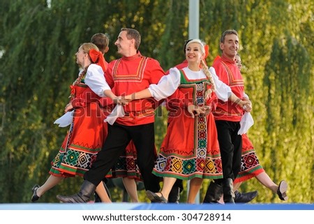 Orel, Russia, August 4, 2015: Orlovskaya Mozaika folk festival, men and women in red Russian suits dancing in the scene