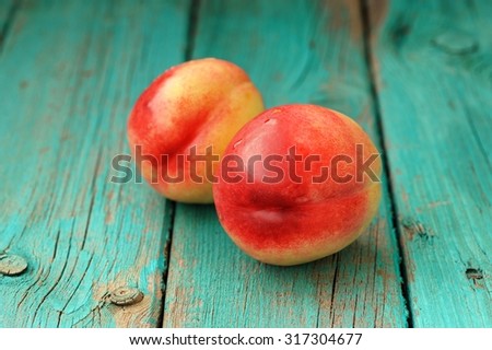 Two fresh ripe whole nectarines with water drops on vintage turquoise table closeup