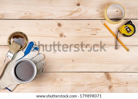 Work gloves, a brush, a can of paint, propelling pencil and ruler on a wooden background