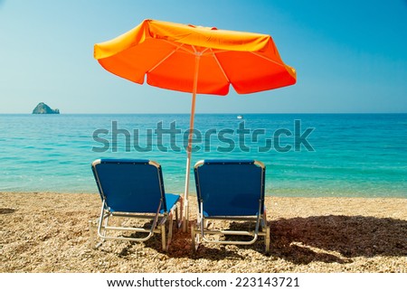 Sunbeds and umbrella (parasol) on Paradise Beach, Corfu Island.  Paradise Beach is one of the most beautiful beaches in Corfu Island. It is located near Liapades village at south of Paleokastritsa