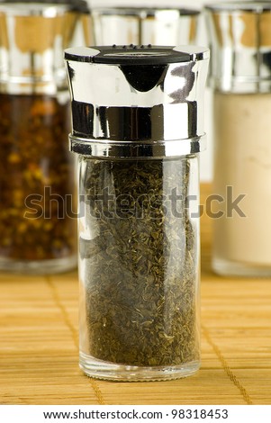dry mint leaves in a glass jar on different spices background over wooden mat