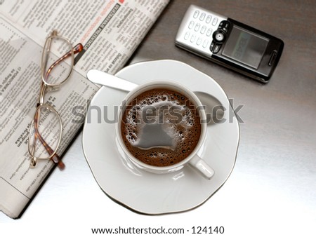 Cup of coffee, newspapers and glasses. Shallow depth of field intentional, focus on coffee.