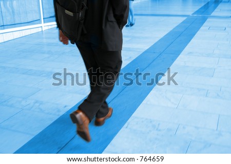 Blue toned motion photo of businessman walking, focus on his right arm
