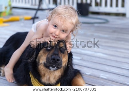 Closeup funny shot of two year old boy playing with large Burmese cross family dog in the backyard, riding on top of trusting canine with copy space. Photo stock © 