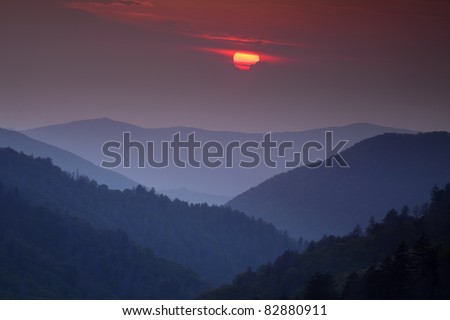 The setting sun slipping behind some clouds looks over the receding ridges of the Great Smoky Mountain National Park as seen from the Morton Overlook. This view is the classic Smoky Mountain scene.