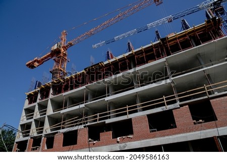 Construction crane near the building under construction Crane. Self-erection crane near concrete building. Construction site. Сток-фото © 
