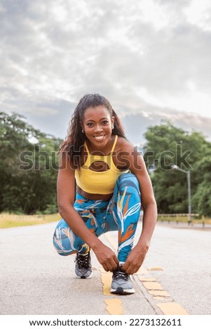 Image, Stock Photo Beautiful girl athlete, african tanned skin. Smiles to camera while Warms up muscles before doing urban yoga training.Leg joints articular gymnastics. Music while training. Sitting floor copy space