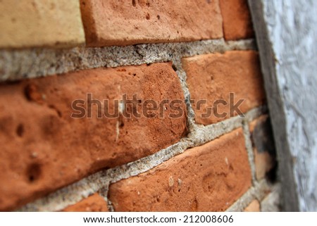 Macro image of angled red brick and mortar wall with wood frame at one side