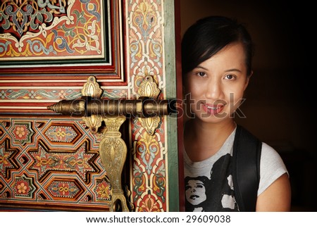A beautiful Asian lady at the side of a beautifully crafted Moroccan door at Putrajaya Botanical Garden, Malaysia