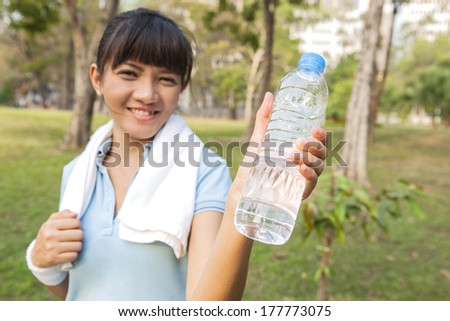 Asian sport woman smiling showing bottle of water in the park
