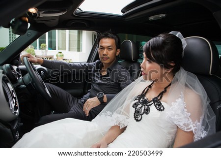 gorgeous wedding couple in car /groom  driving car, bride sitting.