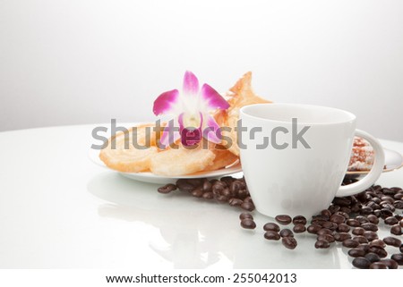 Continental breakfast with assortment of pastries, coffees and flower Orchid in studio shot on coffee beans and white background.