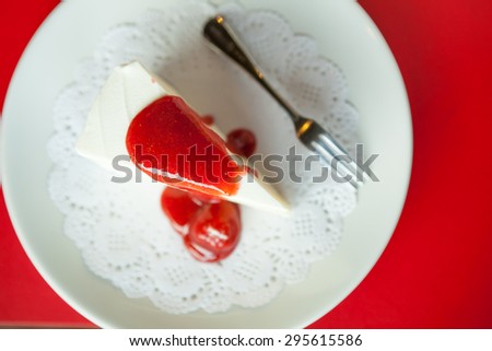 Strawberry cheese cake on white plate and silverware red backgroud