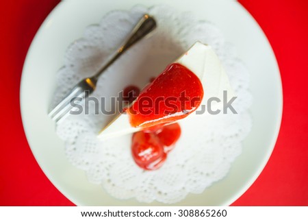 Strawberry cheese cake on white plate and silverware red background