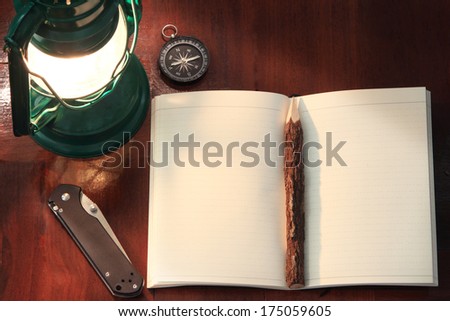 Notebook, pencil, lamp, pocket knife and compass on wood