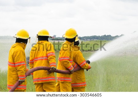 Group of firefighters advance forward putting out a fire.