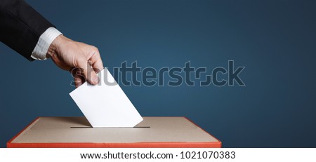 Voter Holds Envelope In Hand Above Vote Ballot On Blue Background. Freedom Democracy Concept