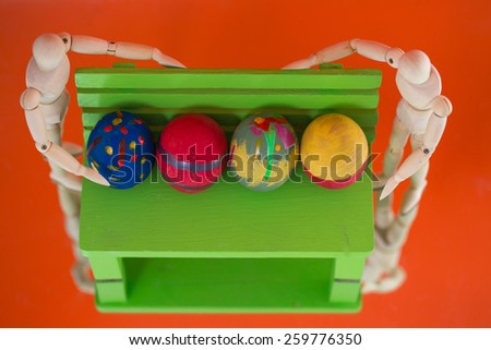 Easter eggs on the green wooden chair ,A wooden dummy, On the ground  orange.