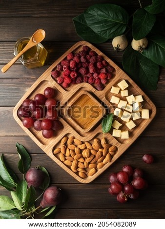 Portion wooden dish on dark wooden background top view. Wooden plate divided into equal 4 section. Compartmentals dish for food, nuts, dessert, fruit and vegetable. food on the plate 商業照片 © 