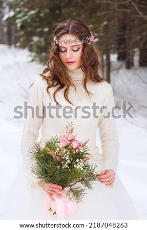Beautiful bride in a white dress with a bouquet in a snow-covered winter forest. Portrait of the bride in nature.Beautiful bride in a white dress with a bouquet in a snow-covered winter forest.  Photo stock © 