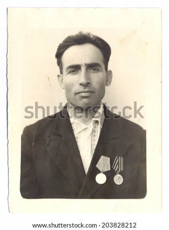 Russia, - CIRCA 1948s: An antique studio portrait of middle-aged man in a suit with medal.