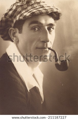 Russia, - CIRCA 1959s: An antique studio portrait of young man in a cap, Smoking pipe.