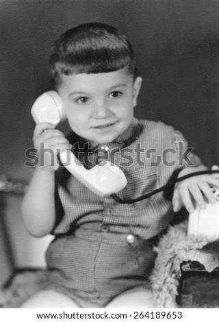 Russia - CIRCA 1967s: An antique Black & White photo of 3-years-old boy calling by phone, posing in the studio.